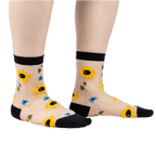 Sheer ankle socks with sunflowers and bees.  Beige background, black cuffs, yellow sunflowers, and blue bees.