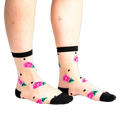 Sheer ankle socks with pink roses, green leaves, and black polka dots on a nude background. Black trim at the top.