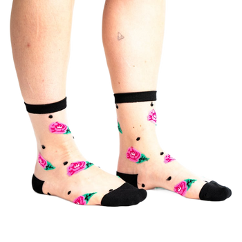 side view of a woman's feet wearing pink sneakers with a white swoosh and black and white floral socks.