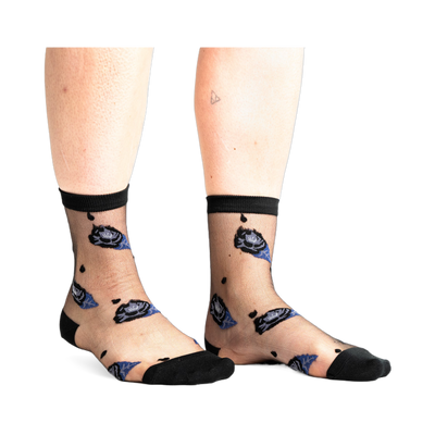 Front view of legs wearing sheer black ankle socks with dark blue and black rose patterns and small black dots on a white background.