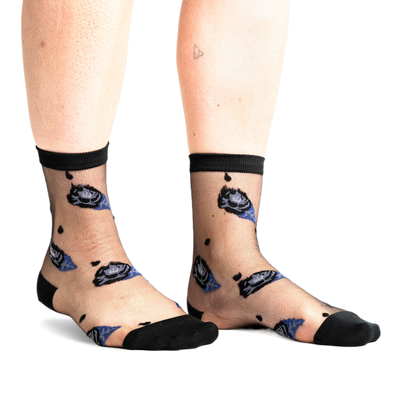 Front view of legs wearing sheer black ankle socks with dark blue and black rose patterns and small black dots on a white background.