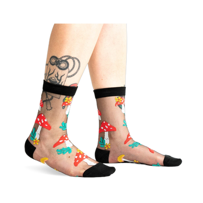 A pair of women's black sheer ankle socks adorned with red and white mushroom and flower designs. 