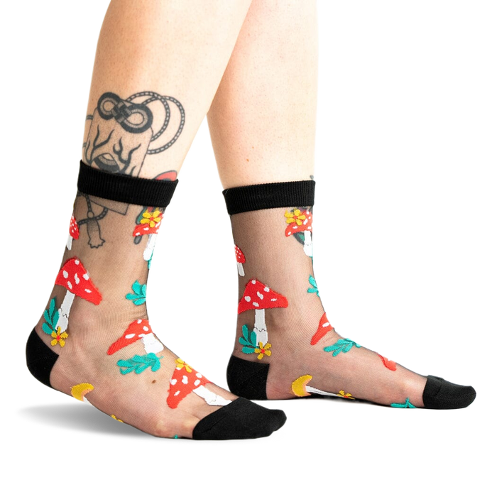 A pair of women's black sheer ankle socks adorned with red and white mushroom and flower designs. 
