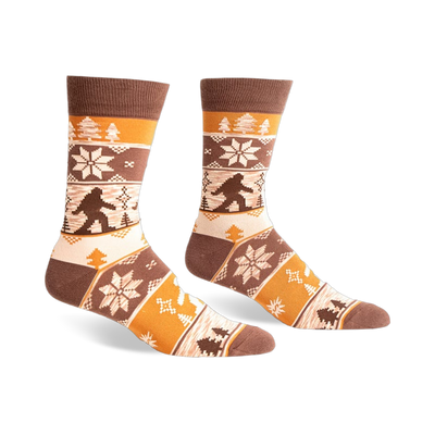 Brown, beige, and orange crew socks with a Bigfoot Fair Isle pattern.  Snowflakes and trees add to the wintery design.