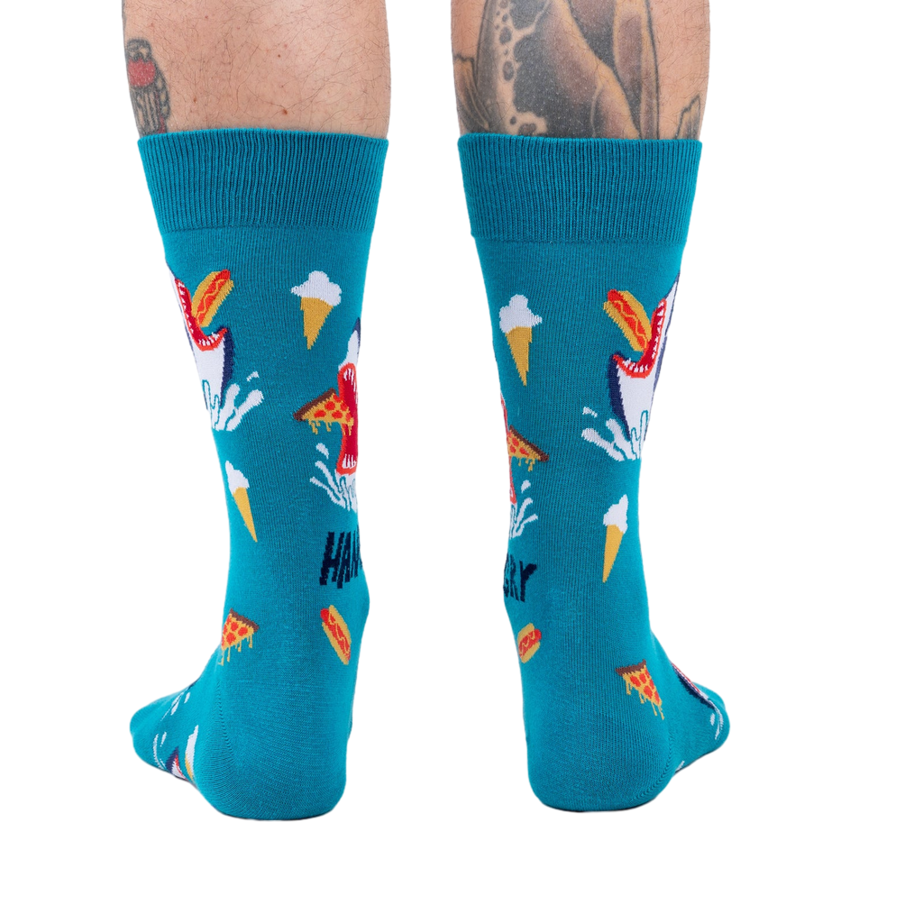 Back view of teal socks with shark and food design on a person's legs. 