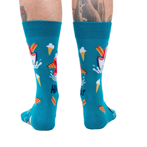 Back view of teal socks with shark and food design on a person's legs. 