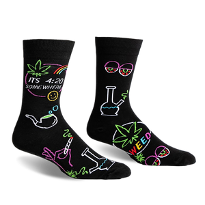 front view of two black socks with colorful marijuana themed designs. one sock has a marijuana leaf, the words gç£its 4:20 somewheregç¥, a rainbow, a smiley face, a smoking pipe, a hand holding a joint and a bong. the other sock has a bong, a marijuana leaf with the word gç£weedgç¥, a pair of glasses with red eyes, and a marijuana leaf.