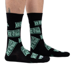 Lifestyle shot of model's legs wearing the black crew socks with a green $100 bill pattern.