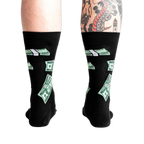 Rear view of the black crew socks with green $100 bill pattern on a model's legs.