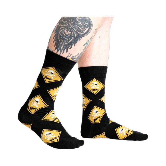 Lifestyle shot of 'Pirate Crossing' socks on a model's legs, showcasing the fit and design on the feet.