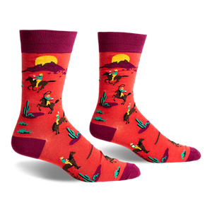 front view of a pair of red socks with a pattern of people riding horses in a desert landscape. the socks are maroon at the top.