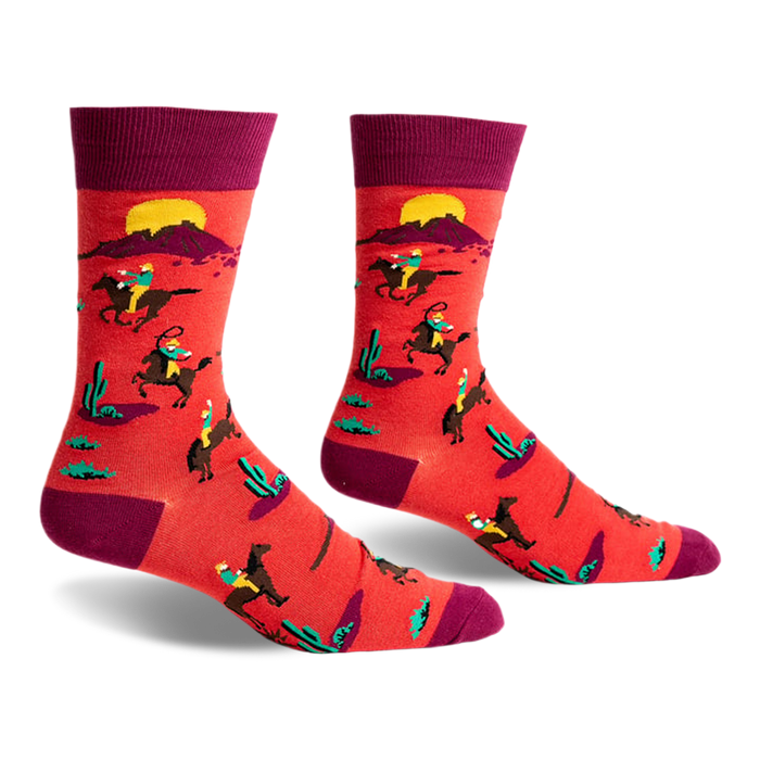 front view of a pair of red socks with a pattern of people riding horses in a desert landscape. the socks are maroon at the top.