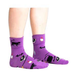 Another lifestyle shot: Model wearing purple 'Witch, Please' socks, viewed from the front.