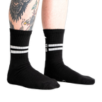 Lifestyle shot showing black Bad Ass Athletic Ribbed socks on a person's legs.