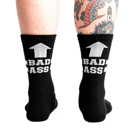 back view of a man wearing black socks with white writing that says "bad ass" with an arrow pointing up.