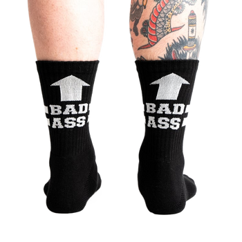 back view of a man wearing black socks with white writing that says "bad ass" with an arrow pointing up.