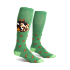 A pair of green knee-high socks with a whimsical design. One sock shows a squirrel roasting a marshmallow by a campfire; the other has scattered pine cones.