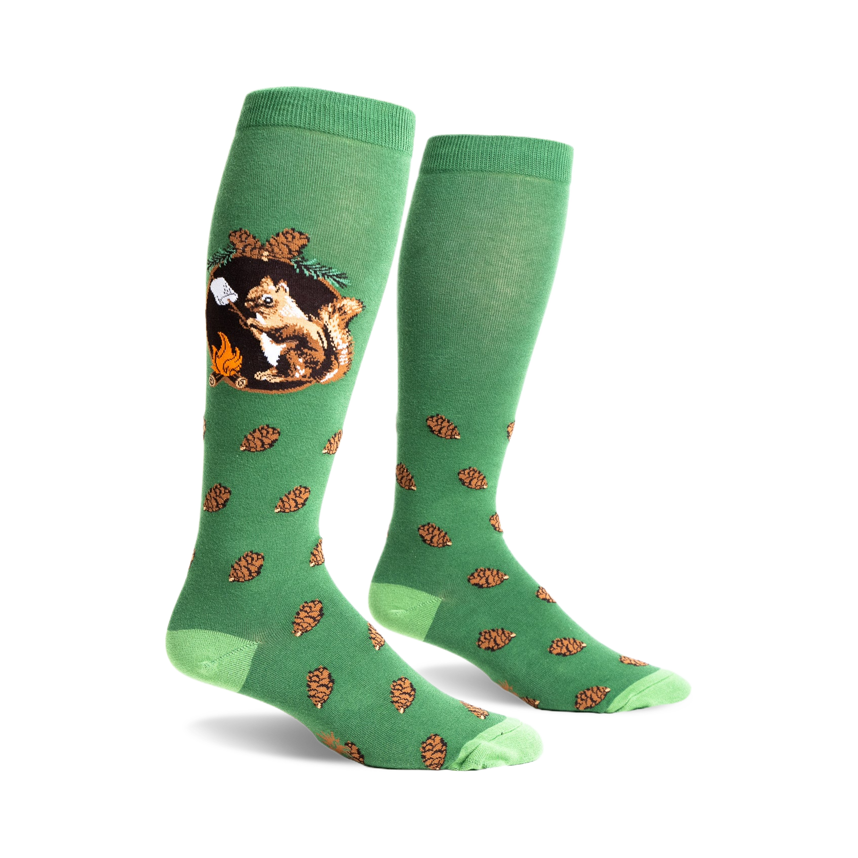 A pair of green knee-high socks with a whimsical design. One sock shows a squirrel roasting a marshmallow by a campfire; the other has scattered pine cones.