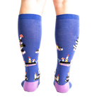 Rear view of model wearing the 'Reading is Magic' knee-high socks, showcasing the full design on both legs.