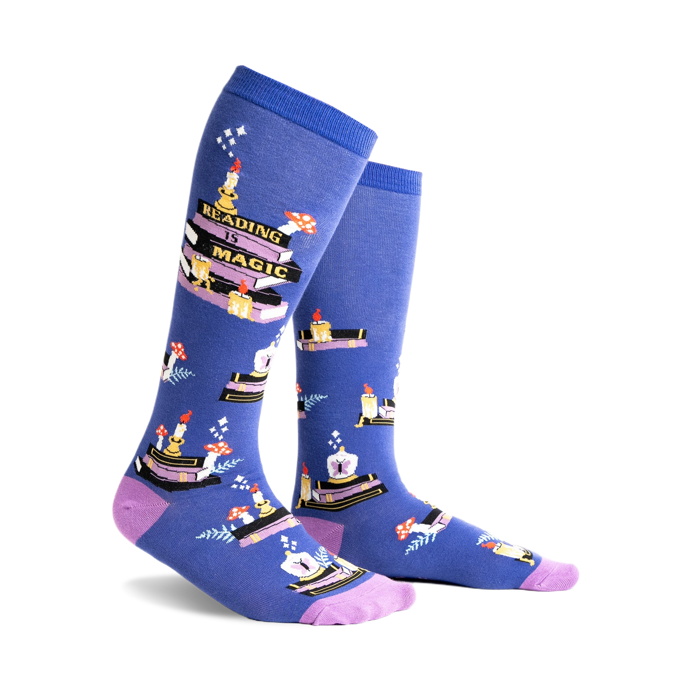 Pair of blue knee-high socks with a whimsical design featuring stacks of books, candles, and mushrooms. Purple accents at the cuff.
