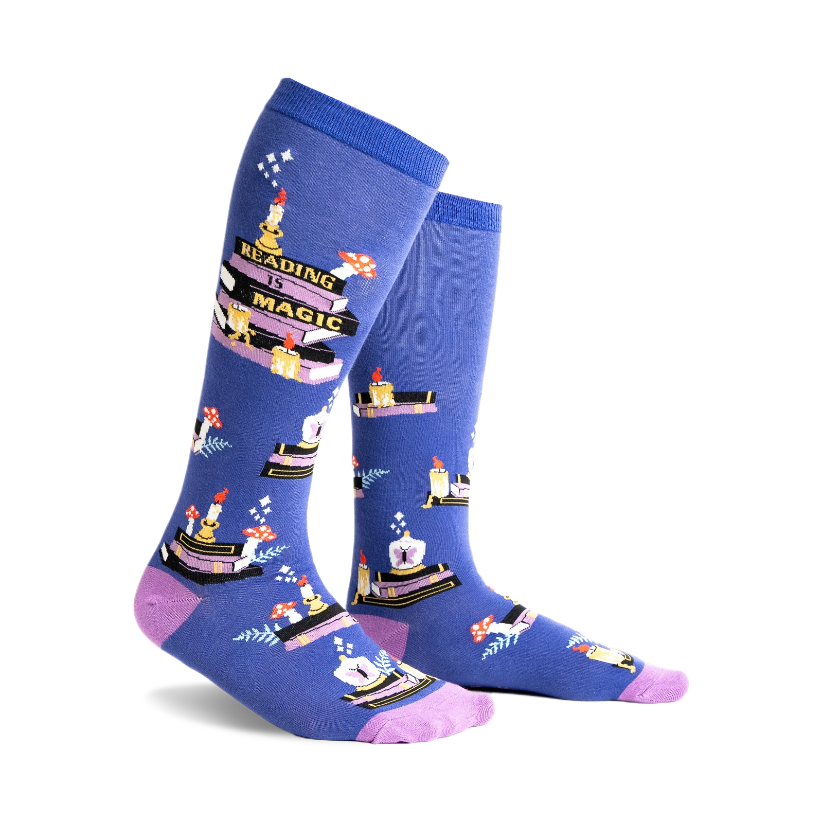 Pair of blue knee-high socks with a whimsical design featuring stacks of books, candles, and mushrooms. Purple accents at the cuff.