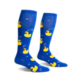 Pair of blue knee-high socks with yellow rubber duckies wearing sunglasses and bow ties, and white bubbles printed on them.