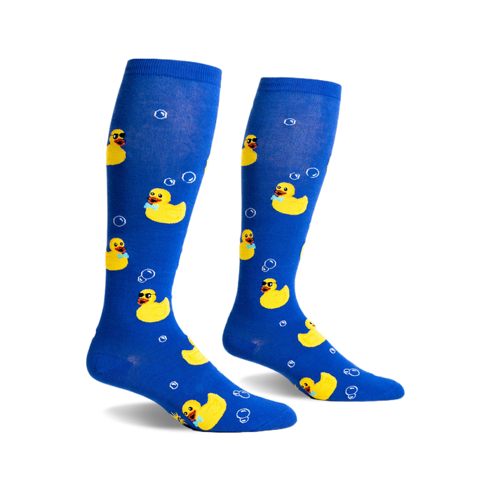 Pair of blue knee-high socks with yellow rubber duckies wearing sunglasses and bow ties, and white bubbles printed on them.