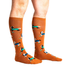 Lifestyle shot of a person's legs wearing the 'Horses Keep Me Stable' knee-high socks. The socks are mustard yellow with a pattern of horses.