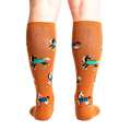 Rear view of a person wearing the mustard yellow 'Horses Keep Me Stable' knee-high socks. The horse pattern is clearly visible from behind.