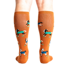 Rear view of a person wearing the mustard yellow 'Horses Keep Me Stable' knee-high socks. The horse pattern is clearly visible from behind.