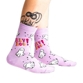 A person's tattooed legs wearing the light lavender "Hey Boo!" ghost crew socks. A "Glows in the Dark" star graphic is visible.