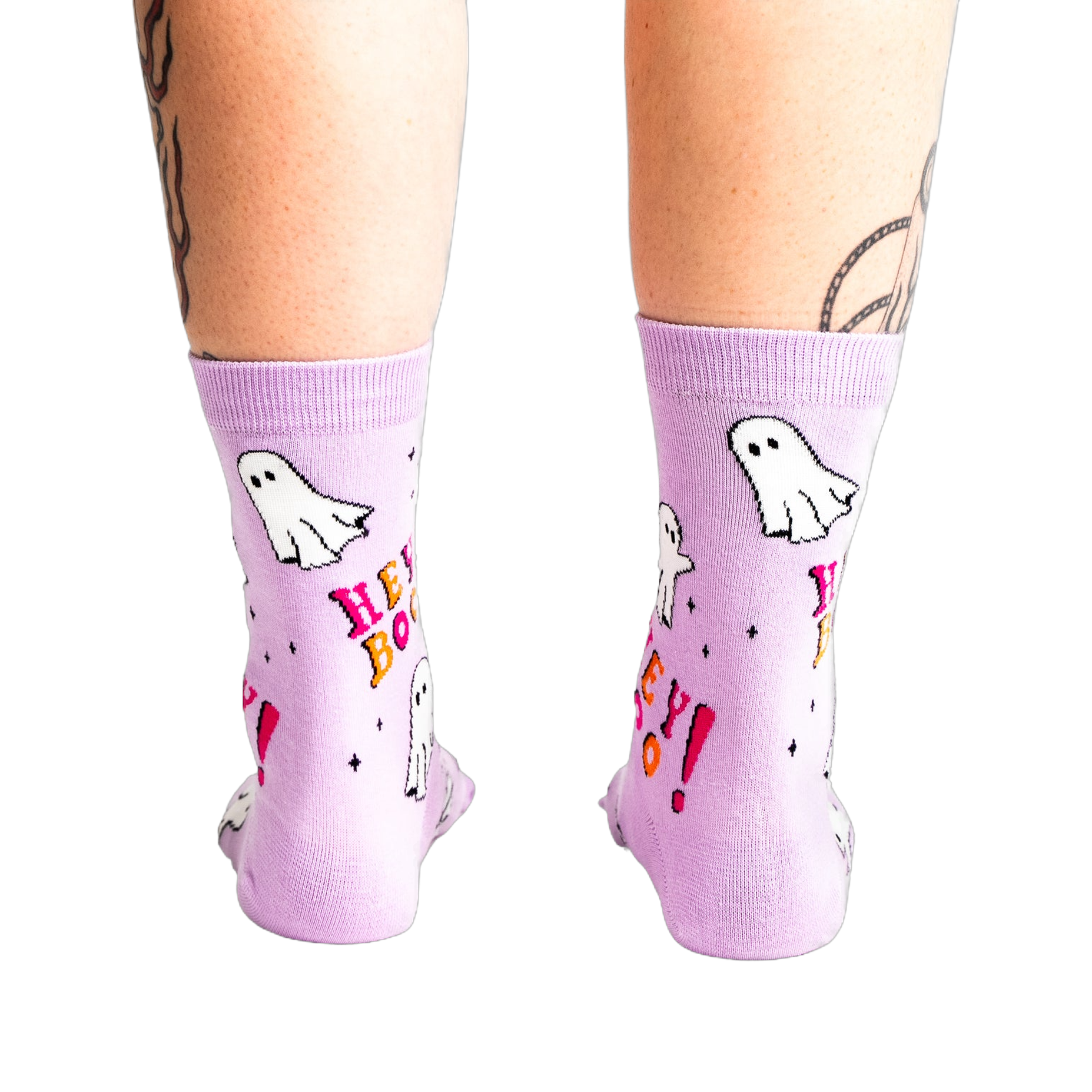 A back view of a person's legs wearing the light lavender ghost "Hey Boo!" crew socks, showing the heel and calf.