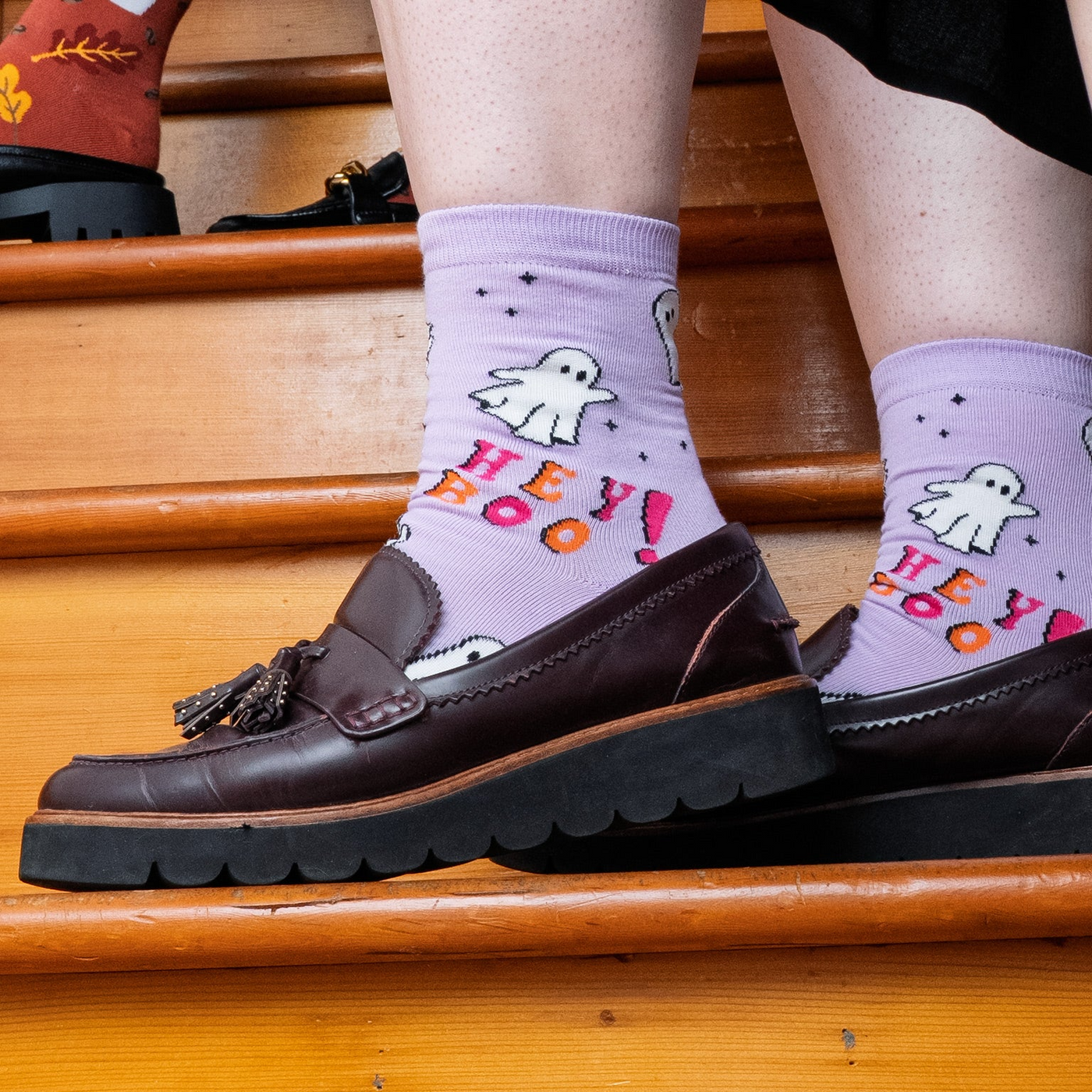 [lf] Person on stairs wearing purple "Hey Boo!" ghost socks and brown loafers.
