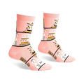 Pair of pink crew socks with a whimsical design of books, plants, and white dogs on a blush pink background.