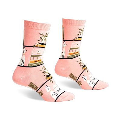 Pair of pink crew socks with a whimsical design of books, plants, and white dogs on a blush pink background.