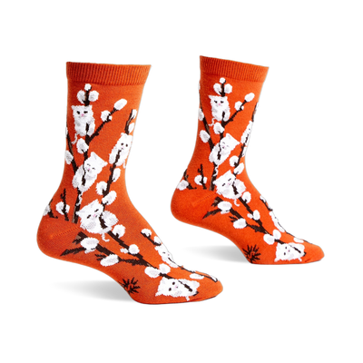 Pair of orange crew socks with a whimsical design featuring white kittens playfully perched on willow branches.