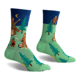 front view of two socks, one on top of the other, featuring a pattern of a bigfoot, a campfire, a forest, and a moon.  the socks are green with blue cuffs.