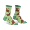 Pair of crew socks featuring a repeating pattern of brown Highland cows and pink thistles on a light green background.