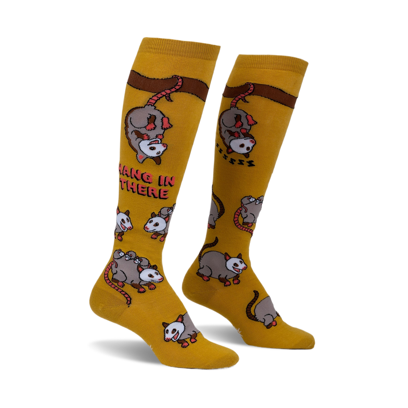 Pair of mustard yellow knee-high socks with playful possum illustrations and the phrase 'Hang in there'.