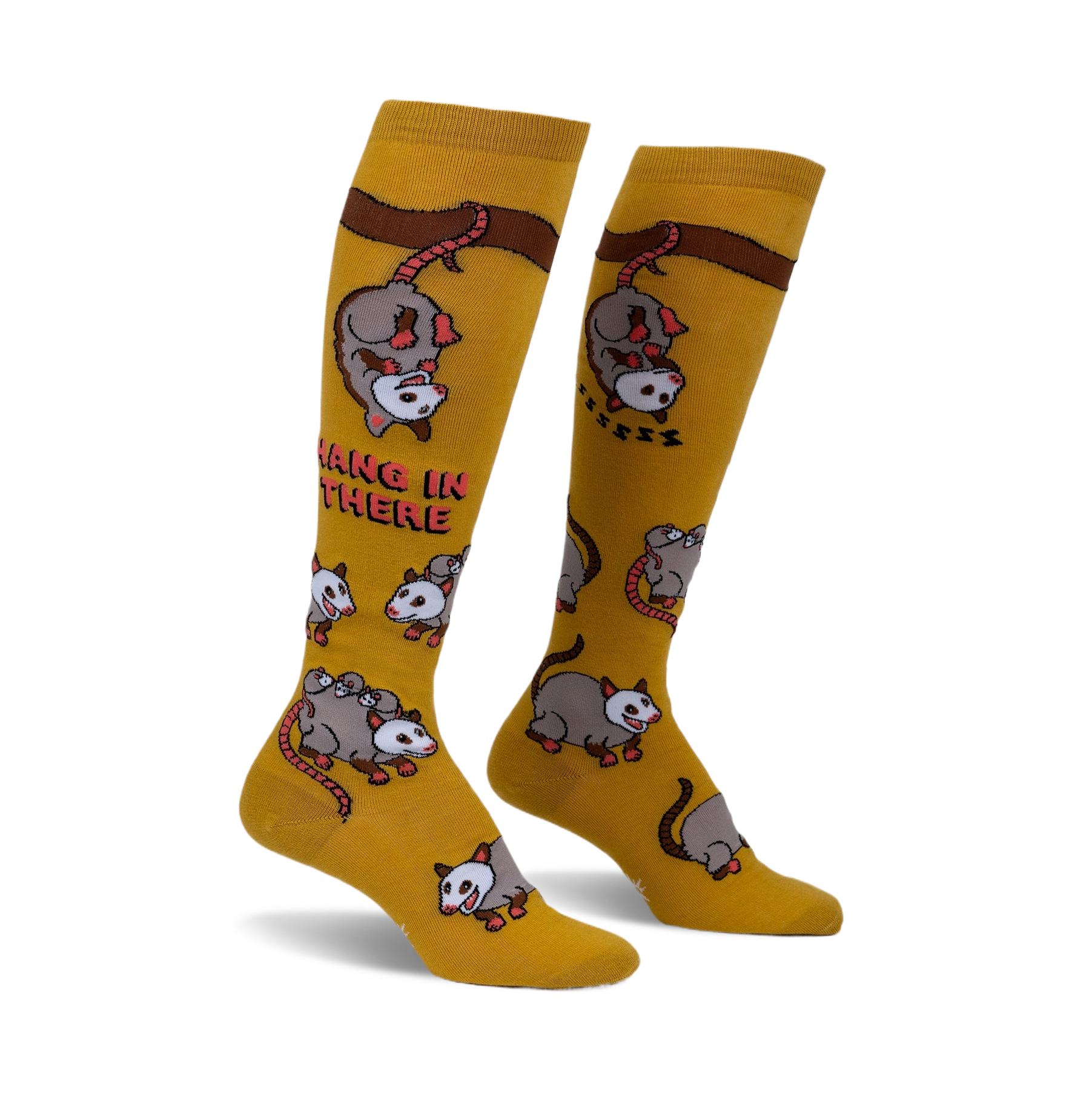 Pair of mustard yellow knee-high socks with playful possum illustrations and the phrase 'Hang in there'.