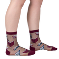 Lifestyle shot showing the socks on a person's legs. The socks are sheer and feature a pattern of books and roses.