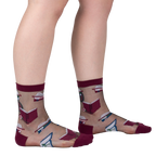 Lifestyle shot showing the socks on a person's legs. The socks are sheer and feature a pattern of books and roses.