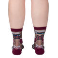 Rear view of a person's legs wearing the sheer socks. The pattern of books and roses is visible.