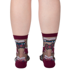 Rear view of a person's legs wearing the sheer socks. The pattern of books and roses is visible.