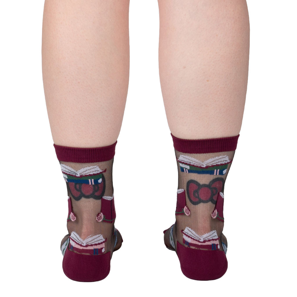 Rear view of a person's legs wearing the sheer socks. The pattern of books and roses is visible.