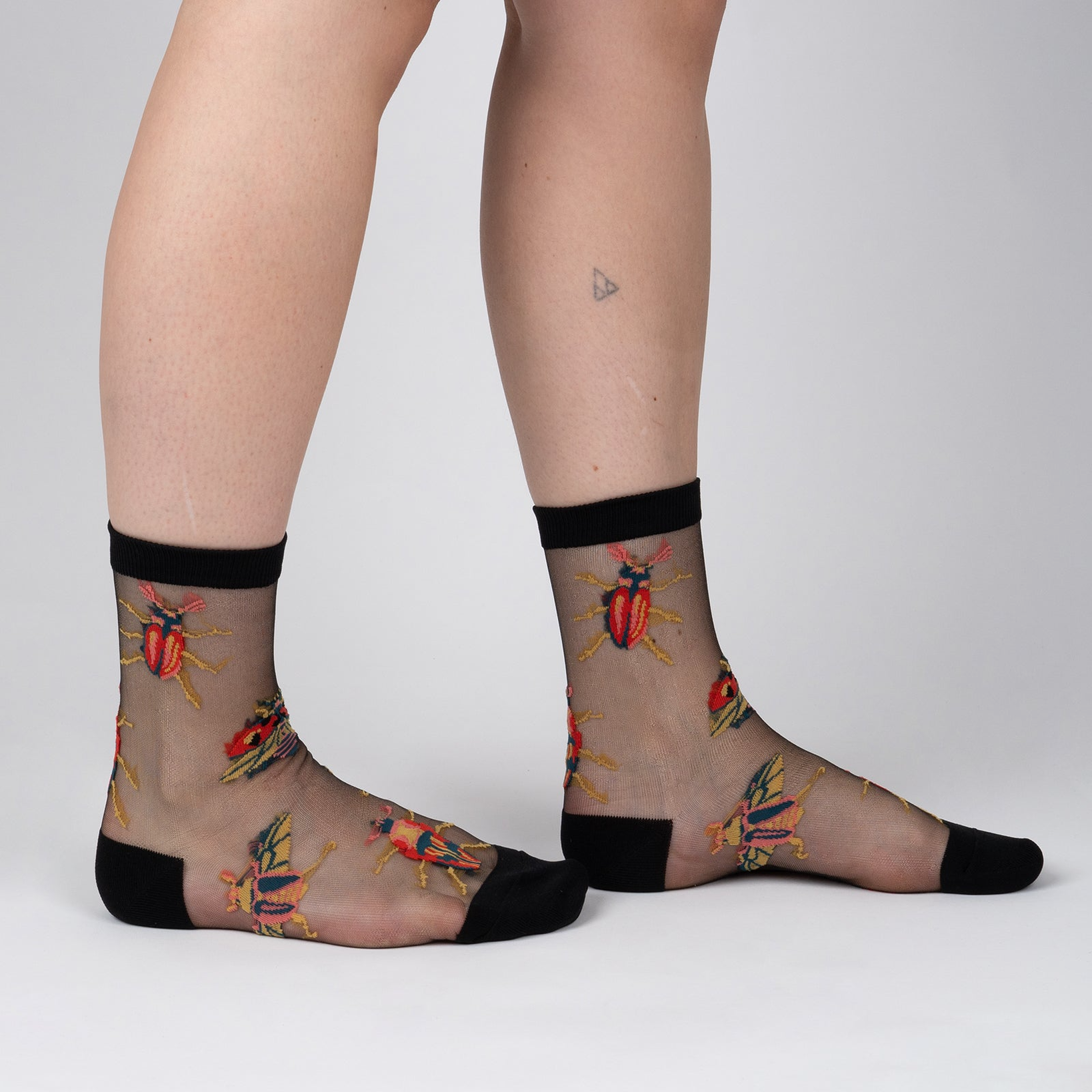 Lifestyle shot of a person's legs wearing the beetle sheer socks.