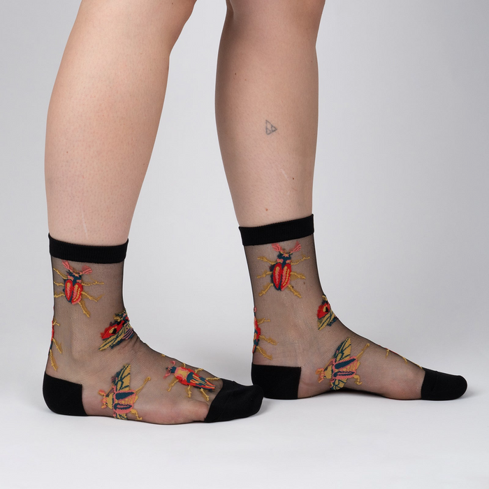 Lifestyle shot of a person's legs wearing the beetle sheer socks.