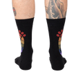 Rear view of the black 'Squatch and Learn' socks, highlighting the full rainbow footprint design on both socks.