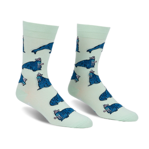 Pair of crew socks. Mint green background with repeating pattern of blue walruses wearing pink hats.