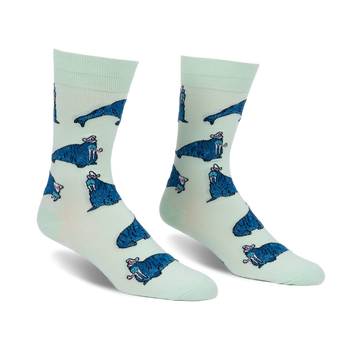 Pair of crew socks. Mint green background with repeating pattern of blue walruses wearing pink hats.